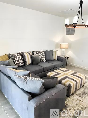 A living room with a grey couch and a rug.