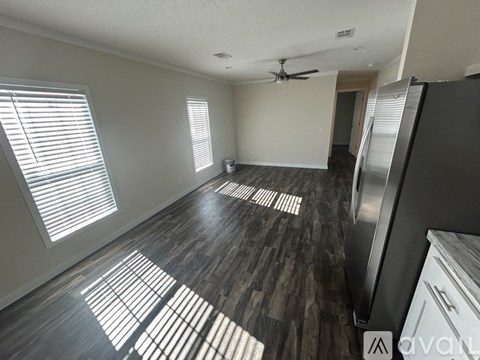 A spacious kitchen with a refrigerator on the right and a ceiling fan above.