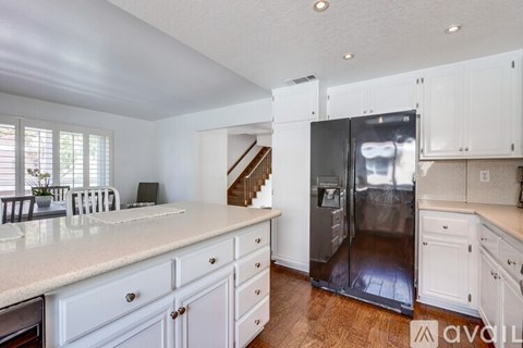 A kitchen with white cabinets and a refrigerator.