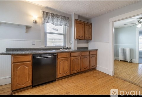 A kitchen with wooden cabinets and a black dishwasher.