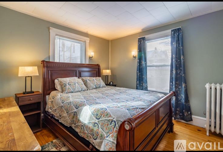 A bedroom with a large bed and a window with curtains.