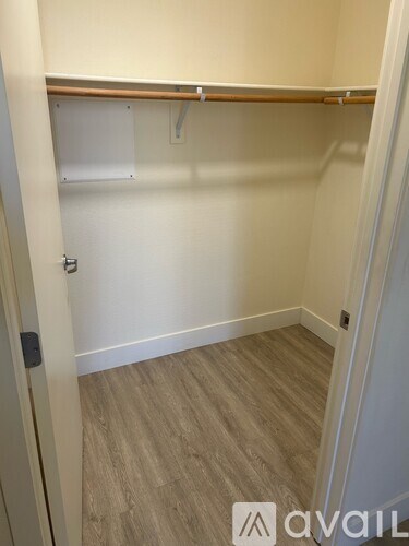 A small, empty room with a wooden shelf and a door on the left.