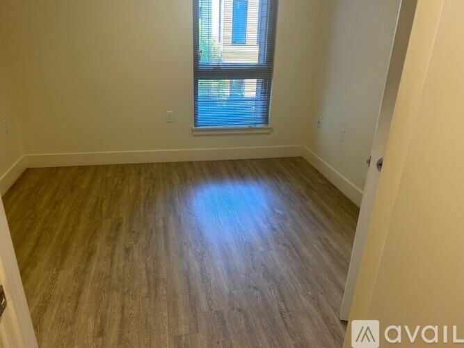 A room with wooden flooring and a window letting in natural light.
