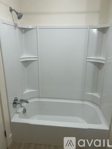 A white bathtub with a shower head and faucet.