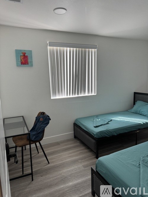 A room with a bed, chair, and window with blinds.