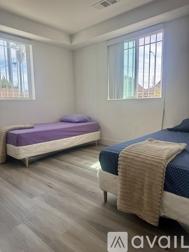 A room with a bed, chair, and window with blinds.