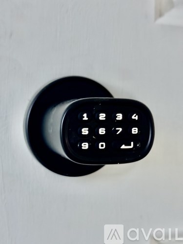 A black keypad with numbers 1 to 10 is mounted on a white door.