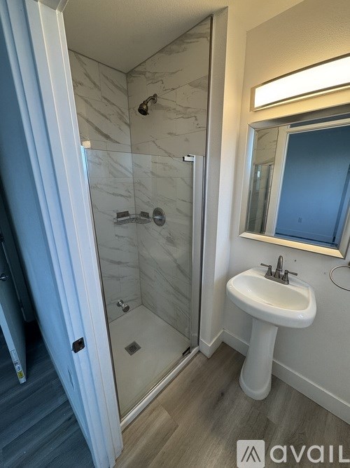 A bathroom with a sink, mirror, and shower.