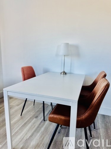 A white table with two brown chairs and a lamp on a wooden floor.
