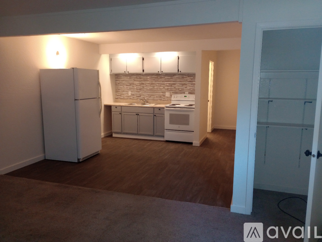 A kitchen area with a refrigerator, cabinets, and a countertop.