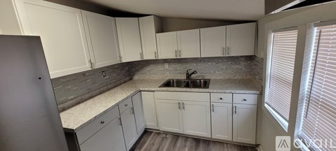 A kitchen with white cabinets and a grey backsplash.
