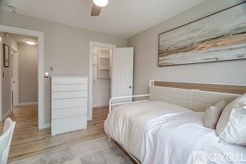 A bedroom with a large bed and a painting on the wall.