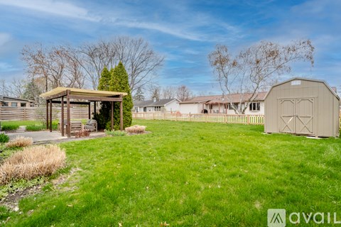 A grassy field with a wooden shelter and a large metal shed.