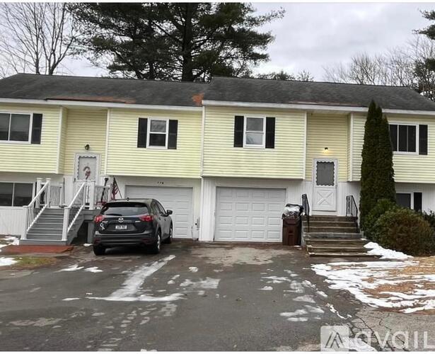 A two-story house with a garage and a car parked in front.