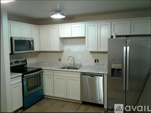A kitchen with white cabinets and a stainless steel refrigerator.