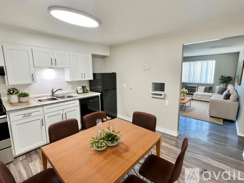 A kitchen with white cabinets and a wooden table with chairs.