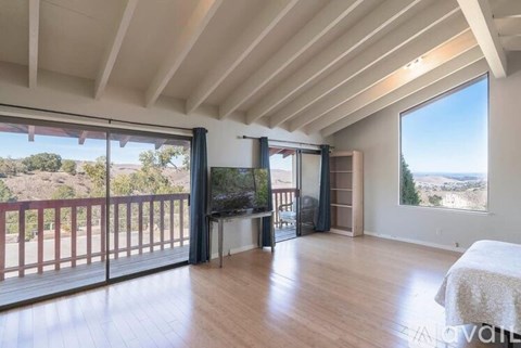 A spacious room with a large bed and a view of the outdoors through the windows.