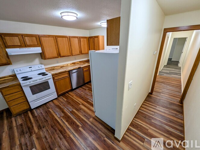 A kitchen with wooden floors and white appliances.