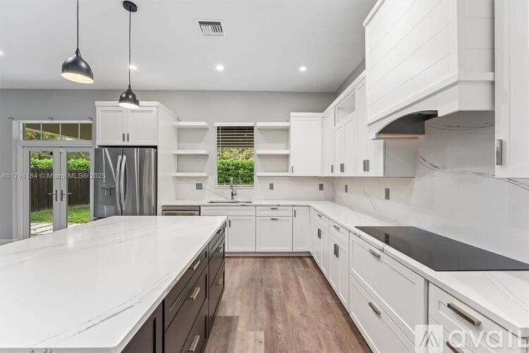 A modern kitchen with white cabinets and a wooden floor.