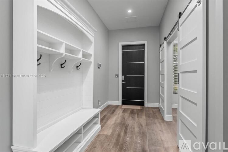 A hallway with a bench, coat hooks, and a door.