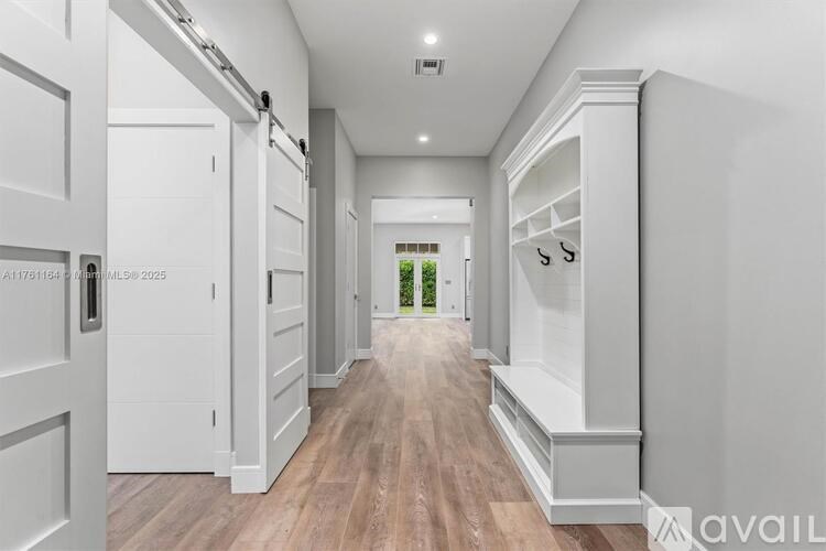 A long, narrow hallway with white doors and a wooden floor.