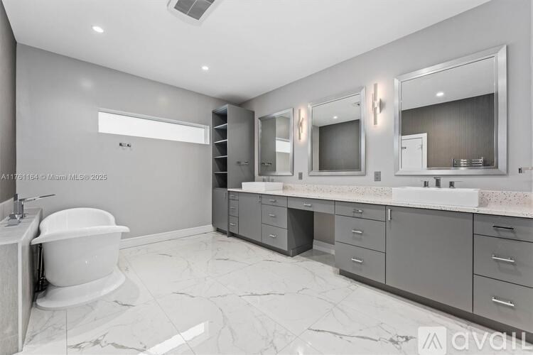 A bathroom with a white tub and grey cabinets.