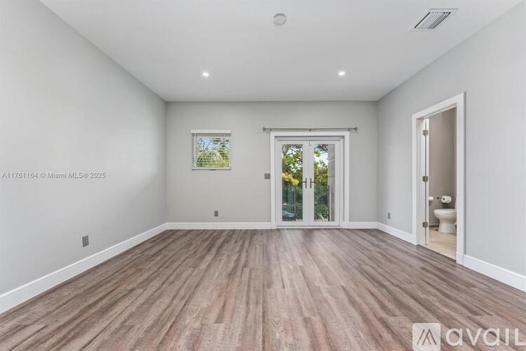 A spacious room with wooden flooring and white walls.