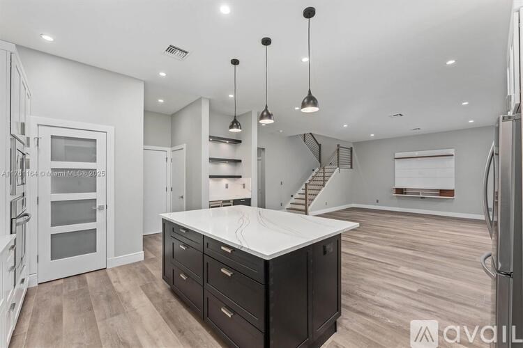 A modern kitchen with a large island and wooden flooring.