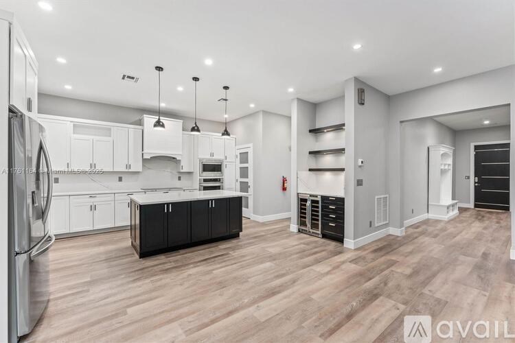 A modern kitchen with wooden floors and white walls.
