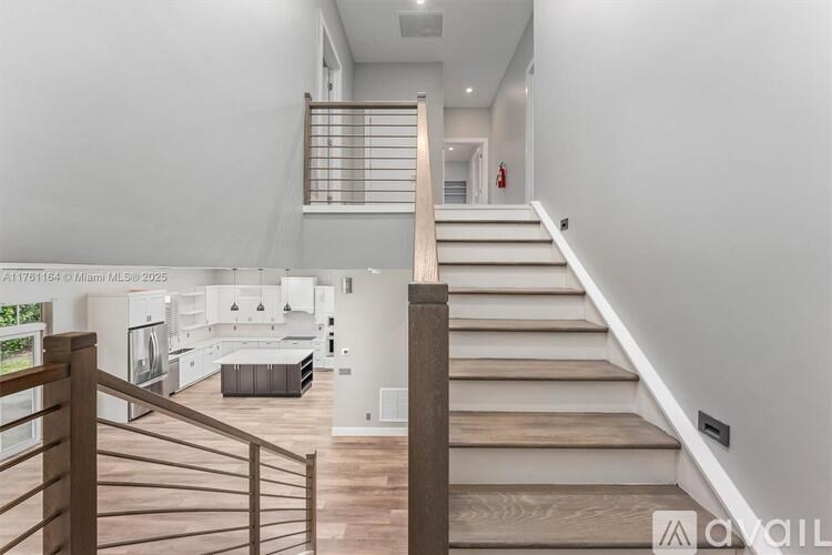 A staircase with wooden steps and a railing leads to a brightly lit room with white walls.