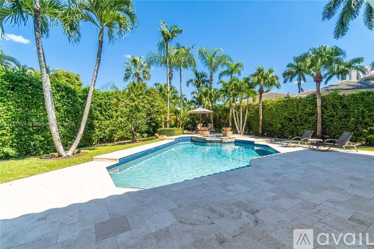 A pool surrounded by palm trees and a hedge.