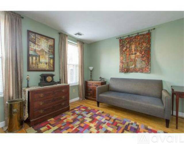 A living room with a grey couch, a wooden dresser, and a rug.