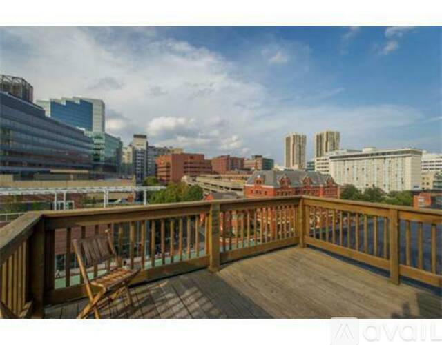 A wooden deck with a chair overlooking a cityscape.