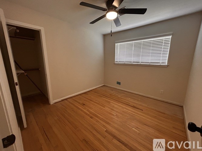 A room with a ceiling fan and a window with blinds.