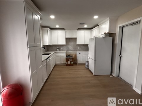 A kitchen with white cabinets and a refrigerator.