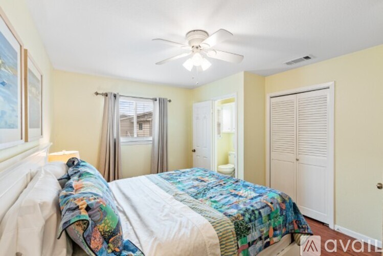 A bedroom with a bed covered in a quilt and a ceiling fan.