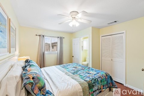 A bedroom with a bed covered in a quilt and a ceiling fan.