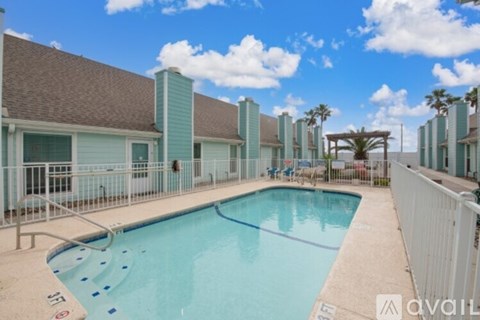 A pool area with a clear blue sky and palm trees in the background.