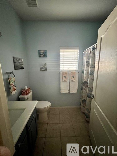A bathroom with a toilet, sink, and towels.