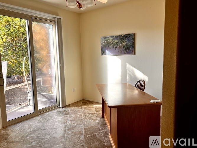 A room with a wooden desk and a painting on the wall.