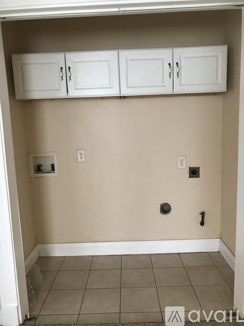 A room with beige walls and a tiled floor with a white doorway leading to another room.