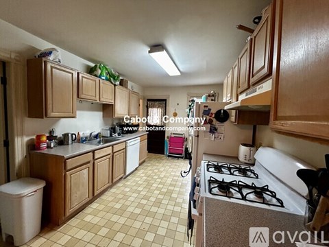 A kitchen with a white stove and wooden cabinets.