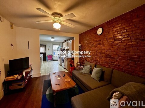 A living room with a brick wall and a ceiling fan.