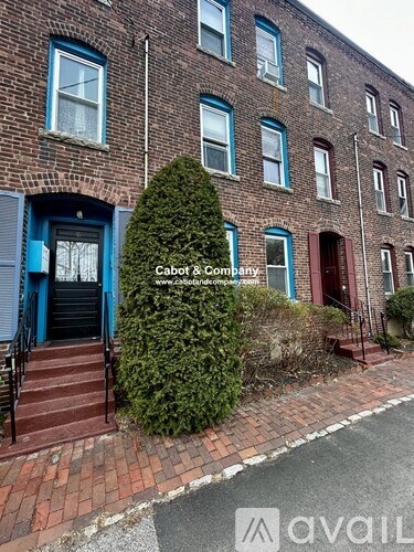 A brick building with a blue door and a sign that says "Cabot & Company.".