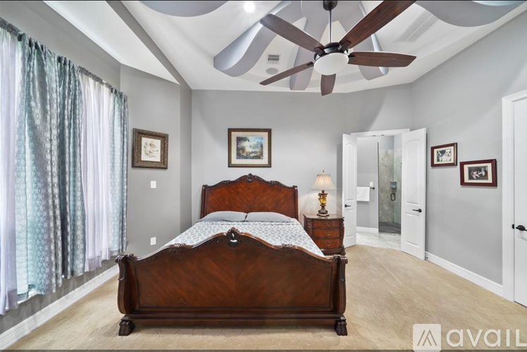 A bedroom with a large bed and a ceiling fan.