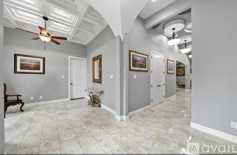 A spacious room with a ceiling fan and paintings on the wall.