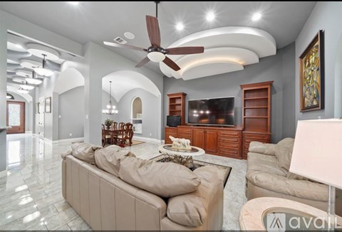 A living room with a beige couch and a ceiling fan.