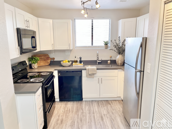 A kitchen with white cabinets and a stainless steel refrigerator.