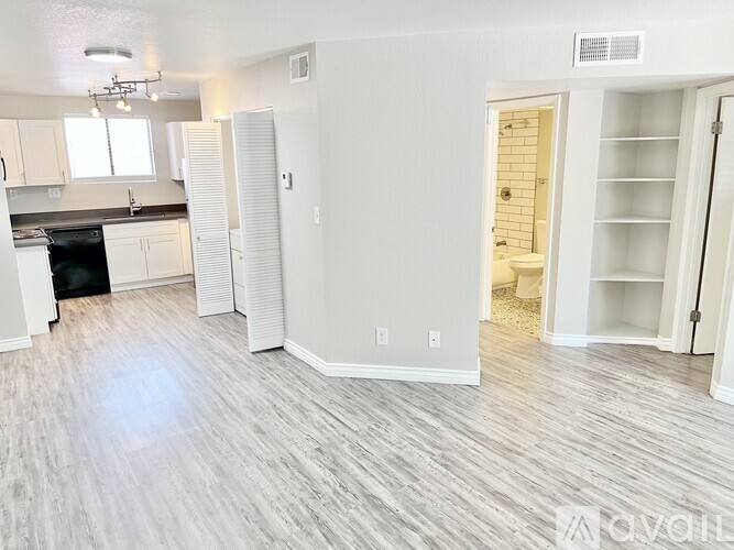 A spacious, empty room with wood flooring and white walls.