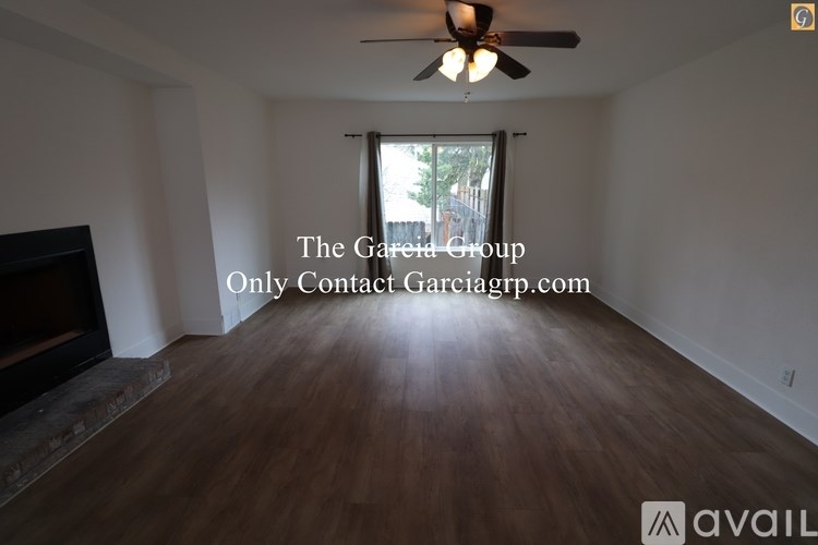 A room with a ceiling fan and a fireplace with a sign that says "The Garcia Group Only Contact Garciagrp.com".